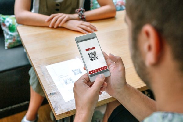 Unrecognizable man scanning restaurant menu QR code on table